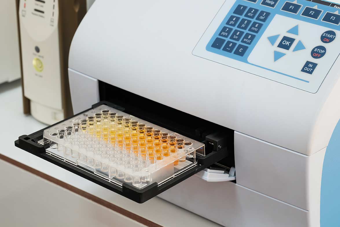 Scientist is putting ELISA plate to measure OD with micro plate reader, Selective Focus